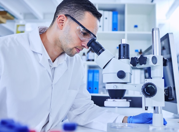 Running a few tests Cropped shot of a handsome young male scientist working with a microscope in his lab