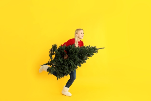 Running girl with spruce on yellow background.