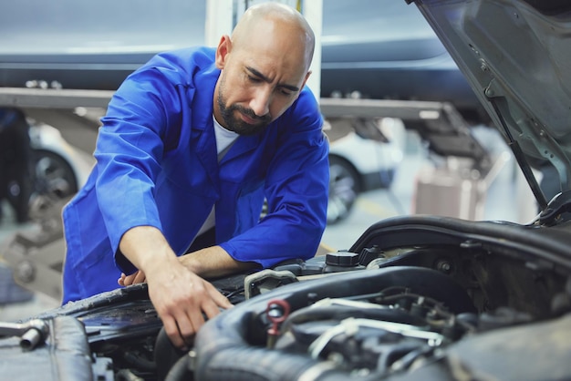 Running his checks Cropped shot of a handsome young male mechanic working on the engine of a car during a service