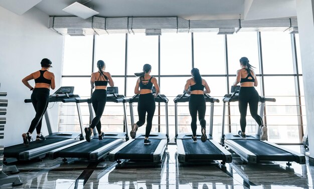 Running on a treadmill Group of young sportive people have crossfit day indoors in gym