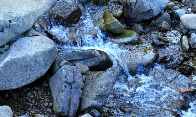 Running water of a small mountain river among mossy stones