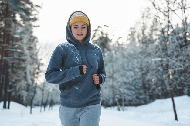 Running woman during her jogging workout during winter and snowy day