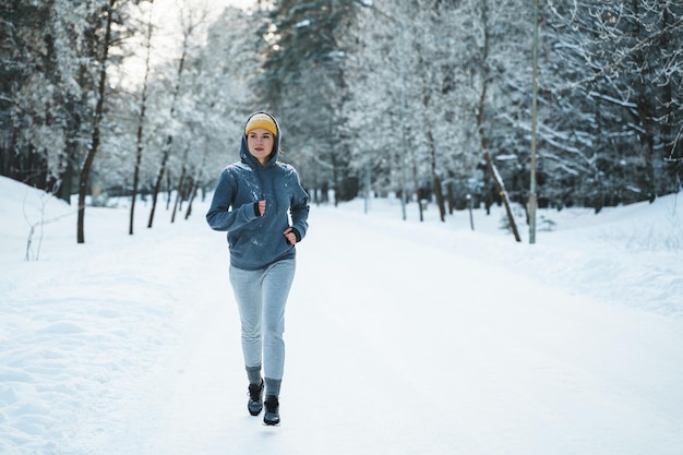 Running woman during her jogging workout during winter and snowy day