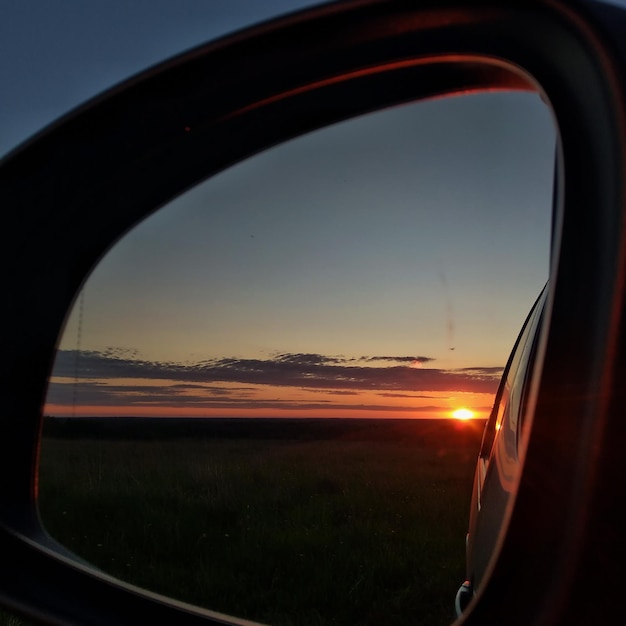 Rural landscape. Reflection of a colorful sunset in the side mirror of a car. Leningrad region,