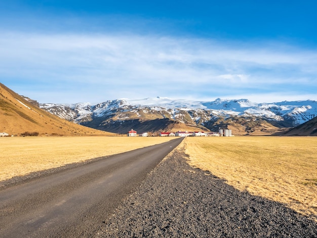 Rural road on drive trip under cloudy blue sky in Iceland