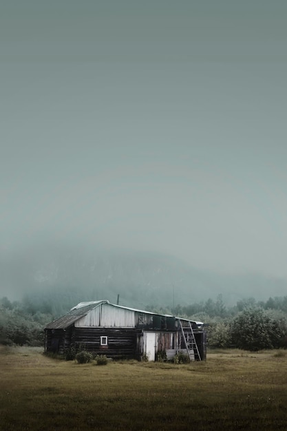 Rural simple house in the forest in the morning at the foot of the mountain in a thick fog gloomy di