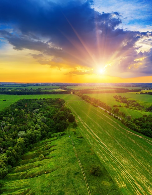 Rural summer sunset landscape with green fields and dramatic colorful sky, natural background, aerial view