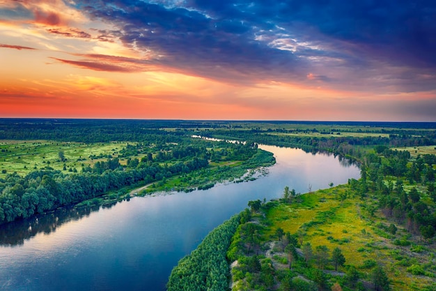 Rural summer sunset landscape with river and dramatic colorful sky, natural background, aerial view