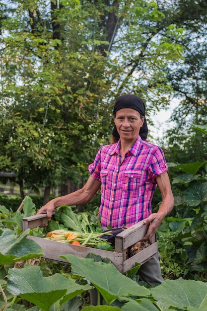 Rural woman with the harvest of vegetables from the organic garden in a wooden crate