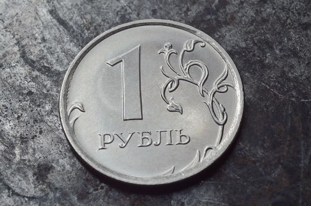 Russian coin with a face value of 1 ruble lies on a dark metal surface closeup