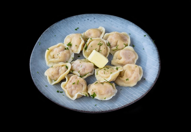 Russian dumplings pelmeni with butter on black background side view