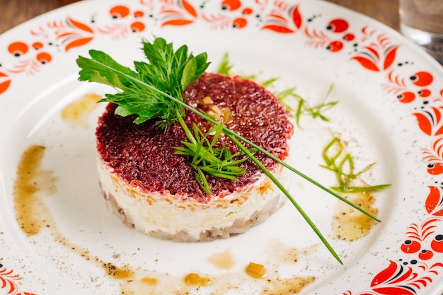 Russian herring salad on plate on wooden table