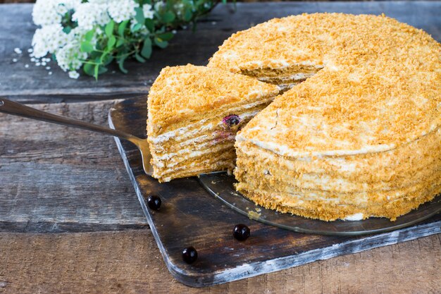 Russian honeycake medovik on wooden table and white background. Cake with berries. Currant cake