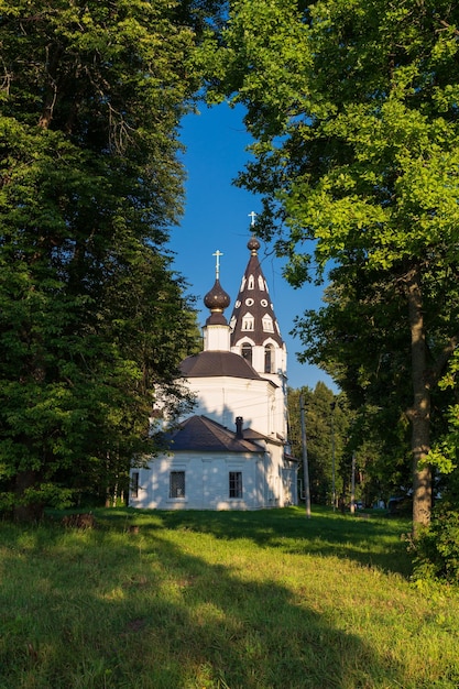 Russian Orthodox church amond big trees framed with birch foliage against clear sky Plyos Russia