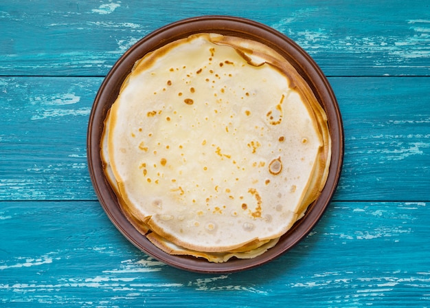 Russian pancakes on a clay plate on an azure table.Top view