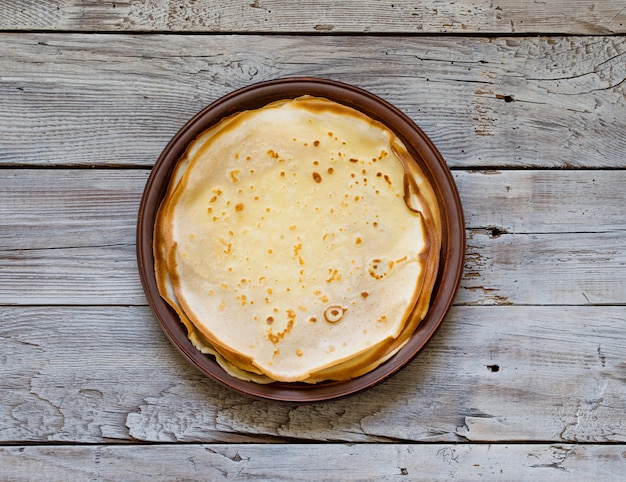 Russian pancakes on a clay plate on a vintage wood