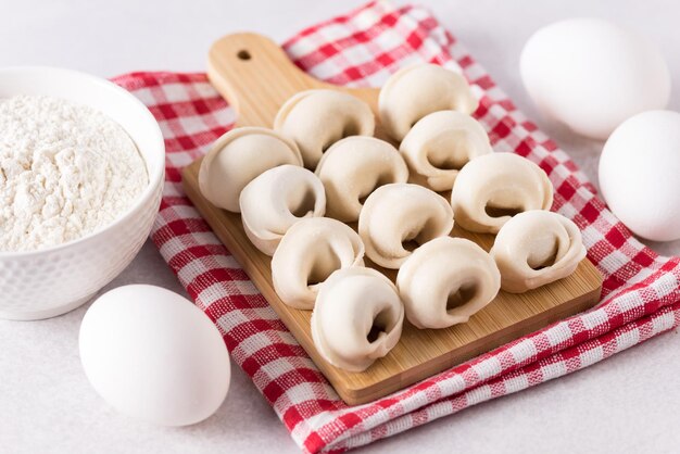 Russian Pelmeni on Cutting Board and Ingredients for Homemade Ravioli or Dumplings