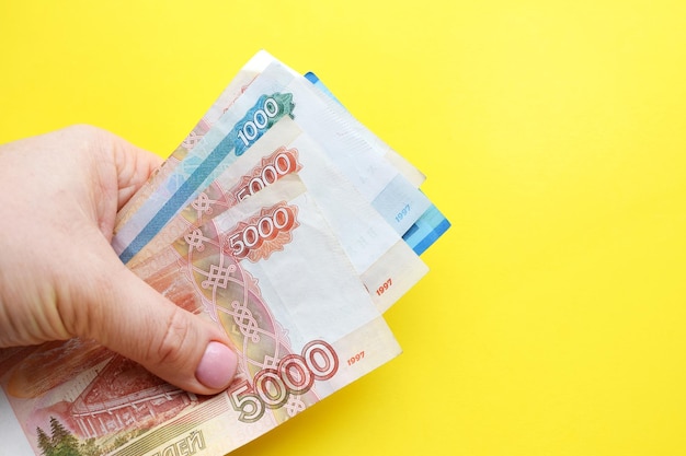 Russian ruble banknotes in a female hand on a yellow background Copy space