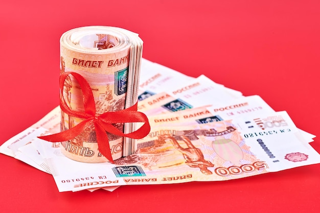 Russian rubles five thousand banknotes bundle of money with red ribbon on red background gift concept