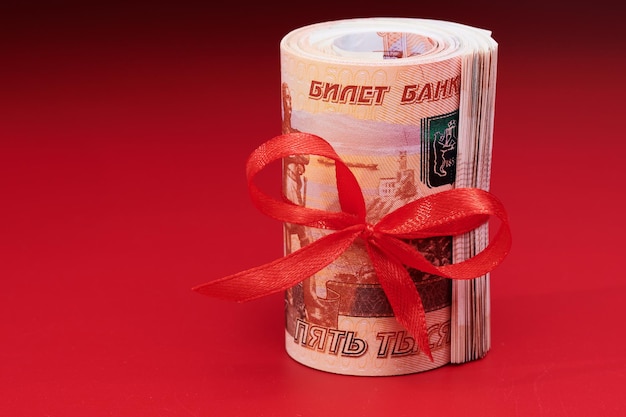 Russian rubles five thousand banknotes bundle of money with red ribbon on red background gift concept