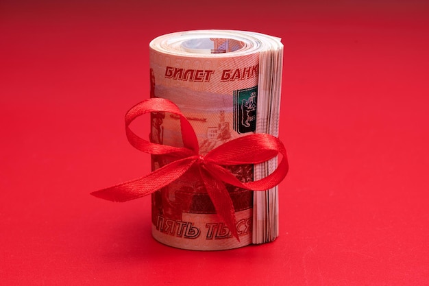 Russian rubles five thousand banknotes bundle of money with red ribbon on red background gift concept