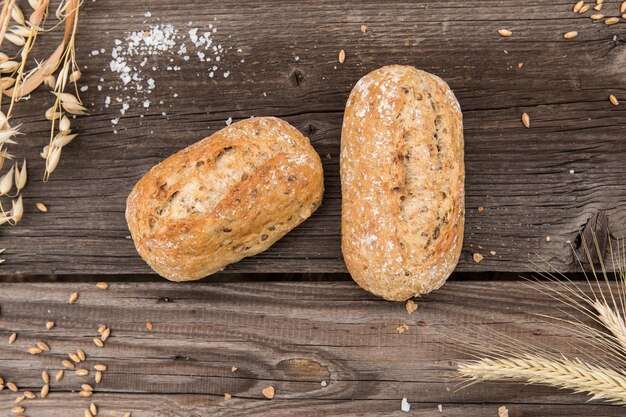 Photo rustic baguette and wheat on an old vintage planked wood table