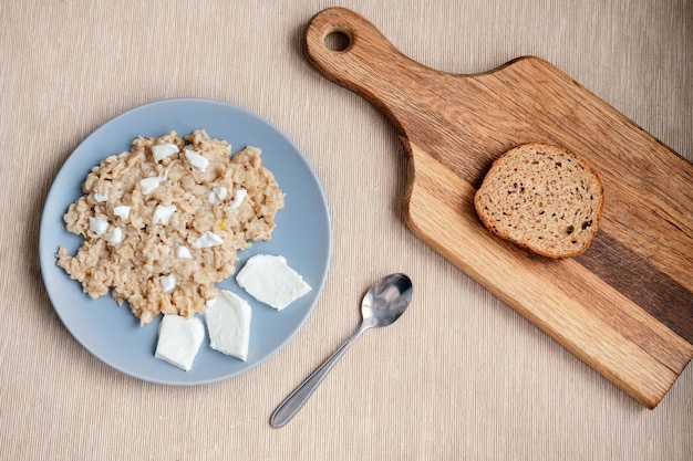 Rustic dairy products breakfast oatmeal with lactosefree cheese and a piece of bread Healthy breakfast on the table