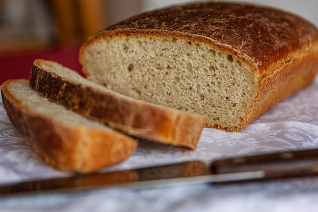 Rustic freshly baked bread with sliced slices on a wooden table. Close-up.