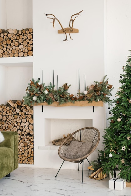 Rustic home interior of the living room with a Christmas wreath fireplace firewood armchair and Christmas tree Decorations for the celebration of Christmas holidays