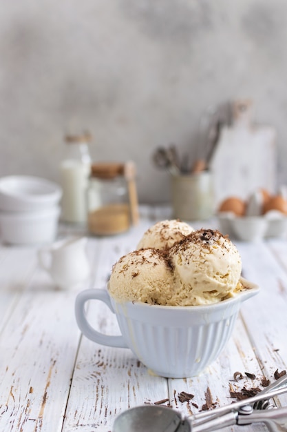 Rustic homemade ice cream in ceramic cup on white wooden table