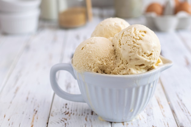 Rustic homemade ice cream in ceramic cup on white wooden table