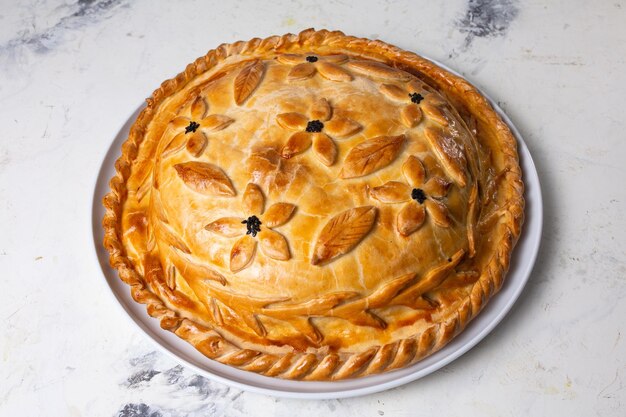 Rustic homemade round meat pie with golden crust isolated on white background