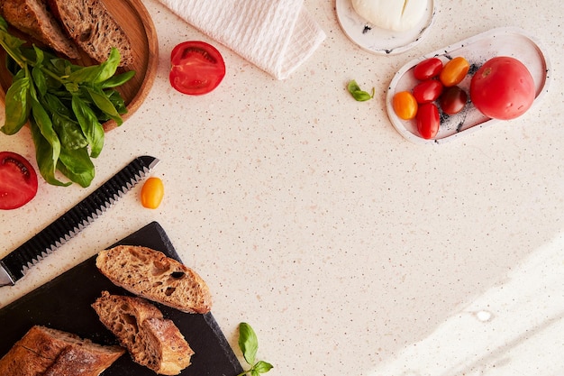 Rustic natural salad under shadows Preparing of traditional caprese salad with fresh tomatoes basil mozzarella and bread Copy space View from above food