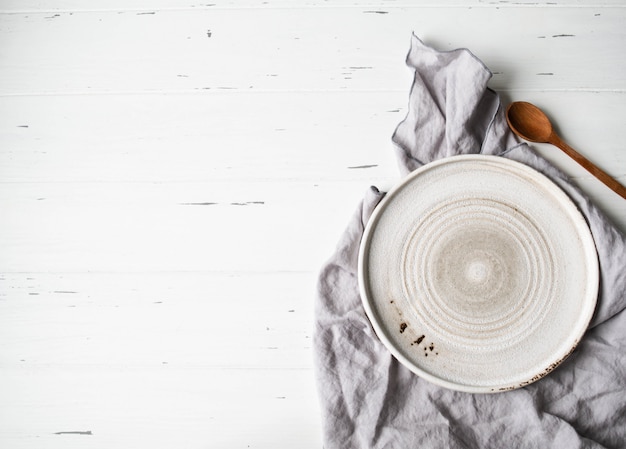 Photo rustic table setting with plates, napkin and wood spoon on white wood table. top view. copy space