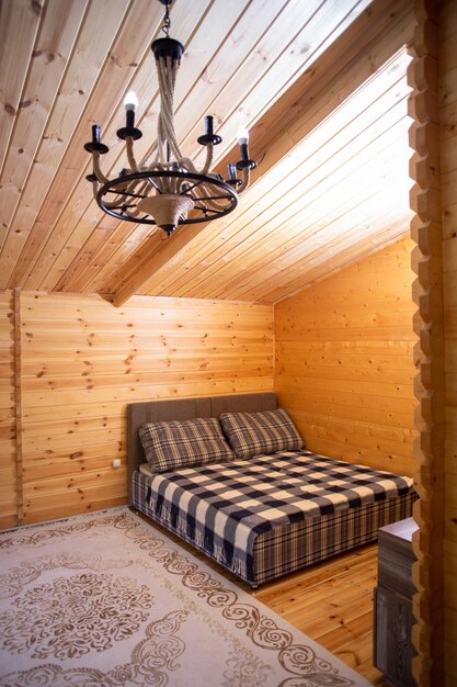 Rustic wooden cabin bedroom with a cozy bed and a beautiful chandelier