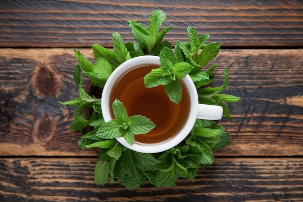 Photo rustic wooden table features cup of golden tea beside fresh herbs