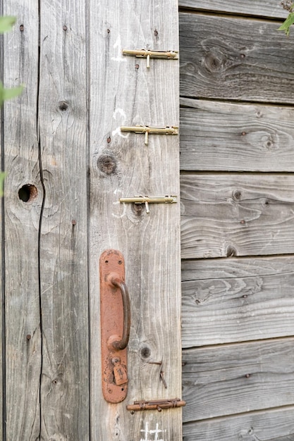 Rusty doorknob and three latches on a wooden barn or toilet door in the countryside