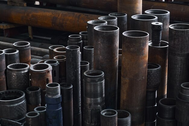 Photo rusty hardware parts of turbodrills of various diameters are on the floor in a workshop