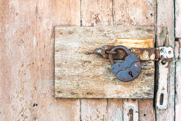 Rusty lock on a texture of old, wooden, orange door, which the old beige paint flaking. the passage is closed. locked.