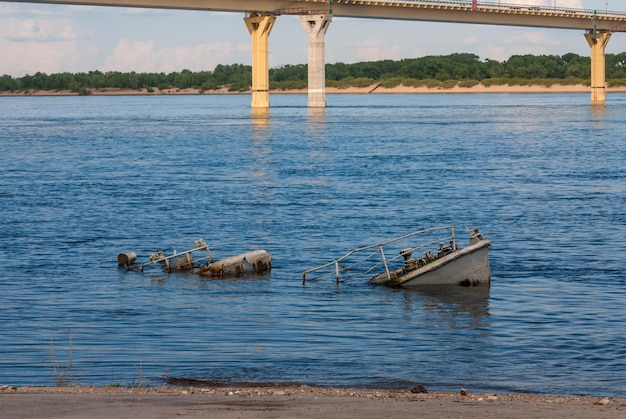 Rusty sinking vessel in a blue river