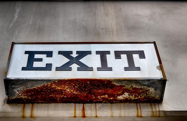 Photo rusty worn exit sign on a concrete wall