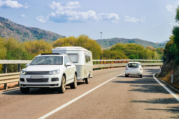 Rv cavaran and car in the road in Costa Smeralda on Sardinia Island in Italy in summer. Motorhome rving on motorway. Camper trailer on highway.