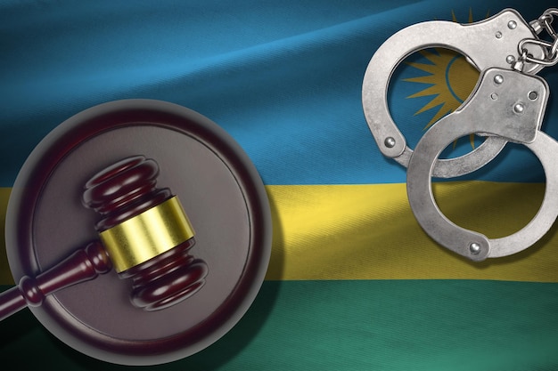 Rwanda flag with judge mallet and handcuffs in dark room Concept of criminal and punishment background for judgement topics