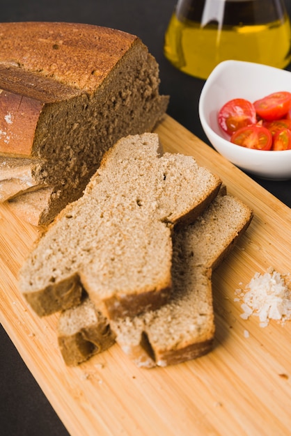 Rye bread, bread slices, tomatoes cherry, oil and salt on cutting board