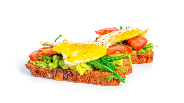 Rye bread sandwich with guacamole, arugula, tomatoes and quail egg isolated. Bruschetta with avocado. Healthy breakfast.