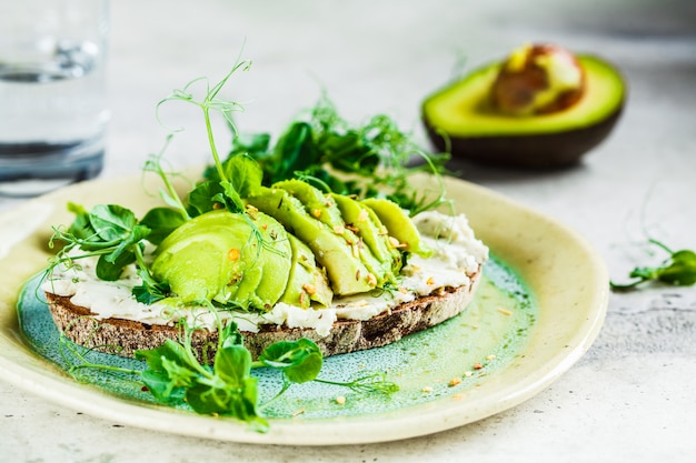 Rye bread toast with cream cheese and avocado on beautiful plate