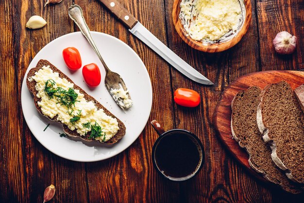 Rye bread toast with processed cheese and garlic on white plate. View from above