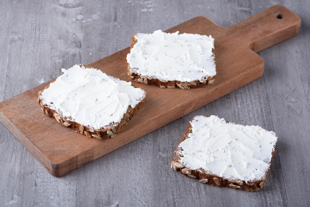 Rye bread with cream cheese on grey table