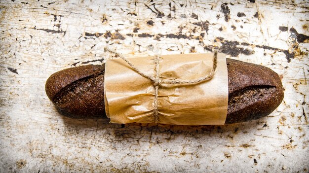 Rye bread wrapped in paper. On  a rustic table.