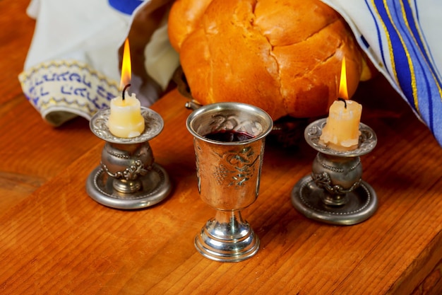 Sabbath image  silver kiddush cup crystal candlesticks with lit candles and challah challahs